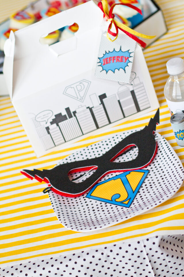 Vintage pop art Super Hero birthday party dessert table with comic book decorations, colorful city skyline backdrop, superhero cake, cupcakes, and candy bar.